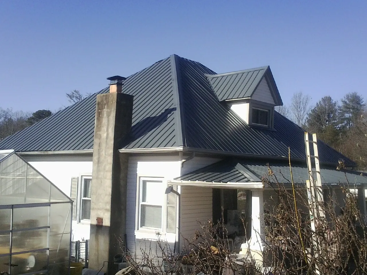 Dark blue standing seam metal roof on a white farmhouse with dormer — Slate & Tile Roof Repair by Roofing Brothers in Tate