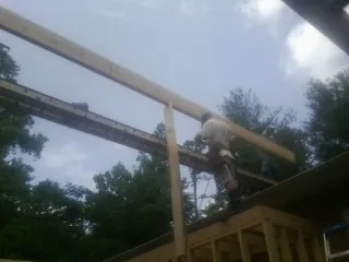 Carpenter setting a ridge beam over a new addition frame — Ice Dam Removal by Roofing Brothers in Tate