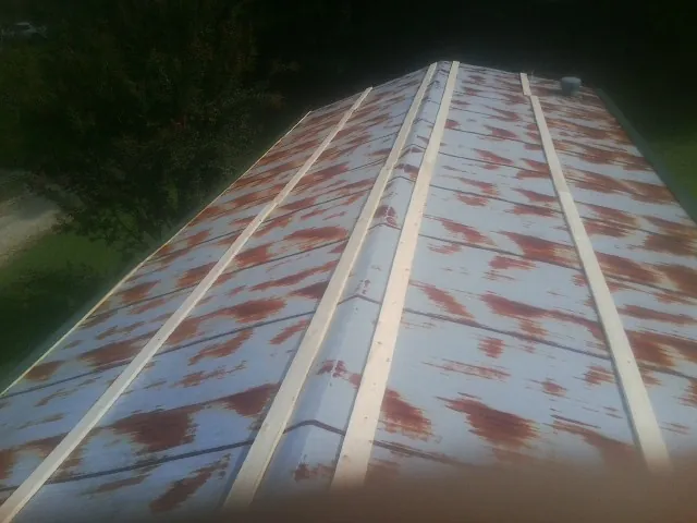 Rusted metal roof panels with new wood purlins before replacement — Storm Damage Roof Repair in Tate by Roofing Brothers