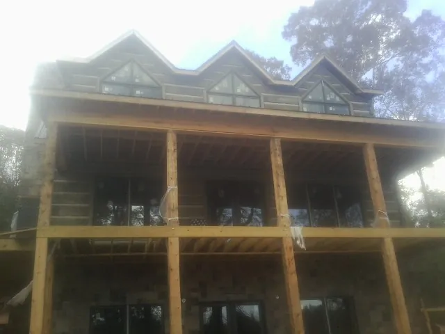 Dormers and porch framing on a large log home under construction — Roof Coating work by our crew in Tate