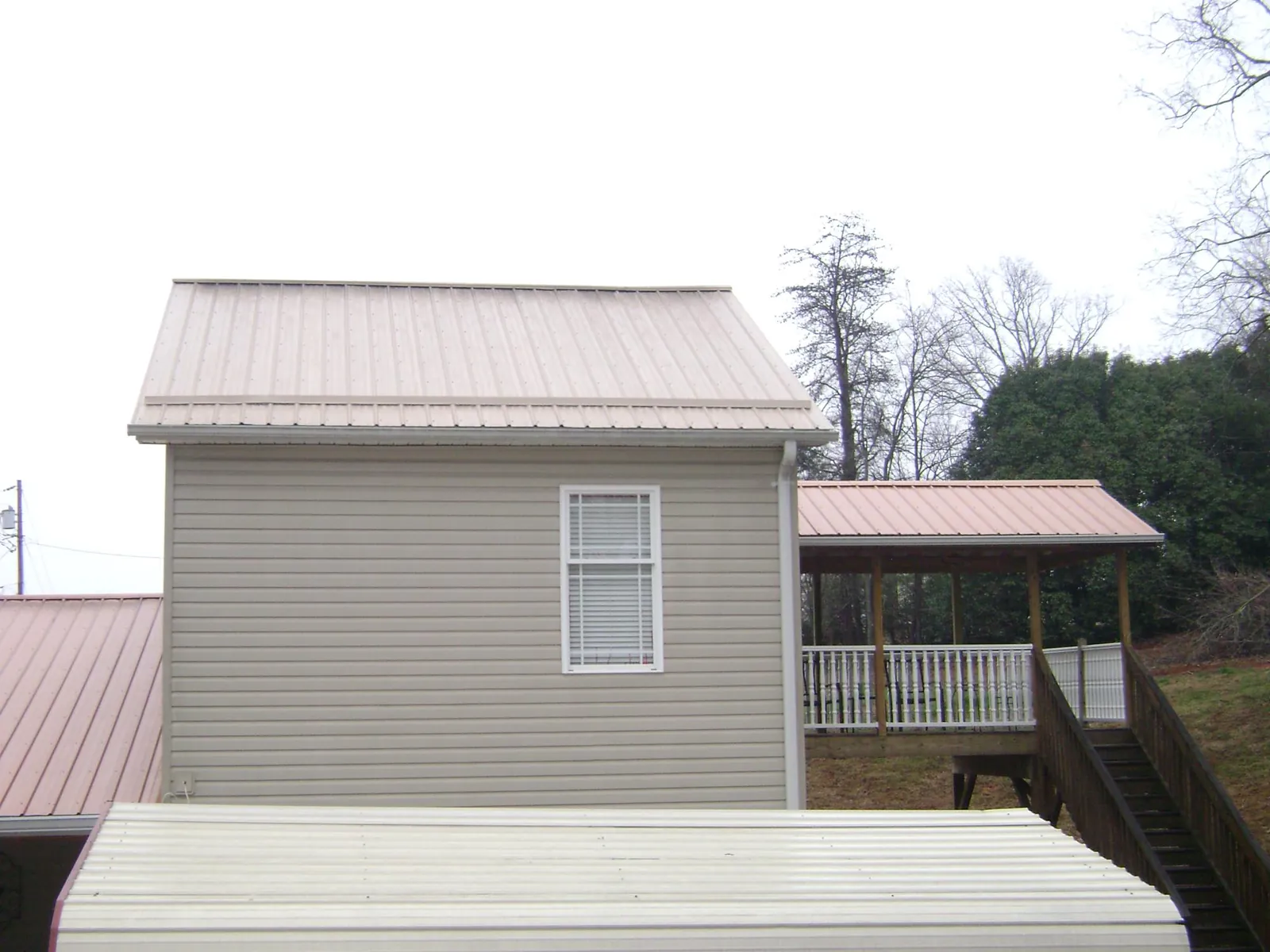 Tan metal roofs on a two story addition and attached porch, from a Roof Replacement job in Tate