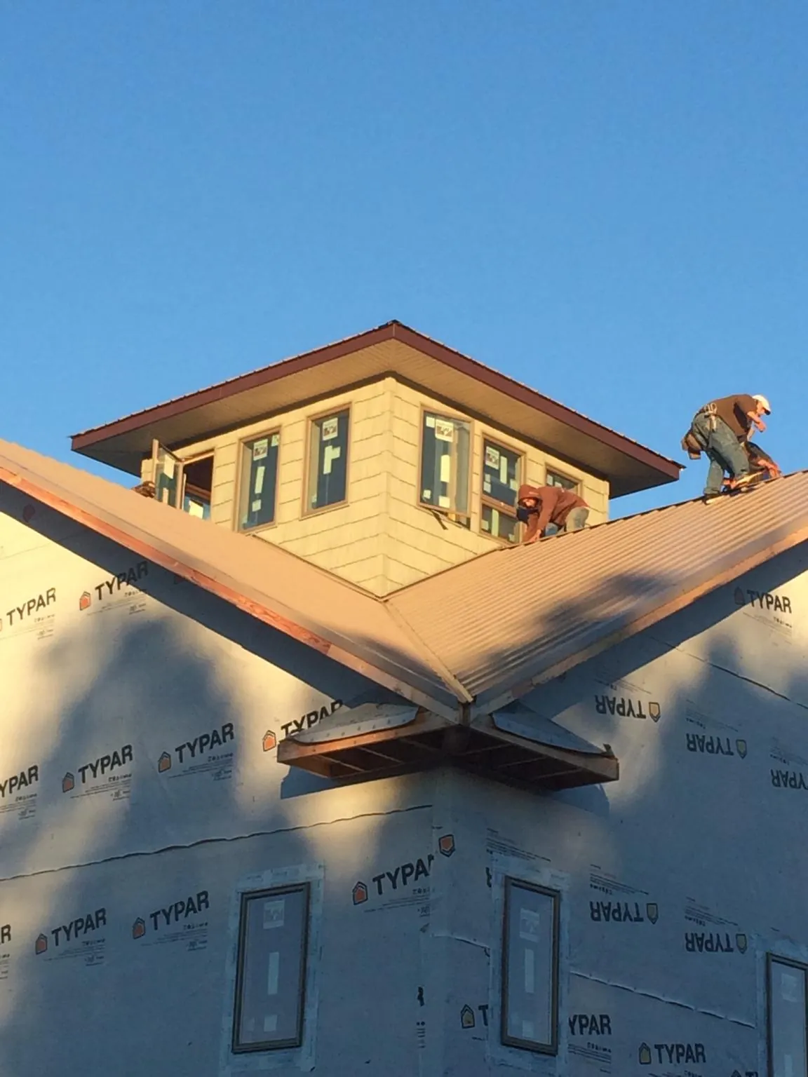 Roofers working around a rooftop cupola on a new metal roof at sunset — Roof Waterproofing in Tate by Roofing Brothers